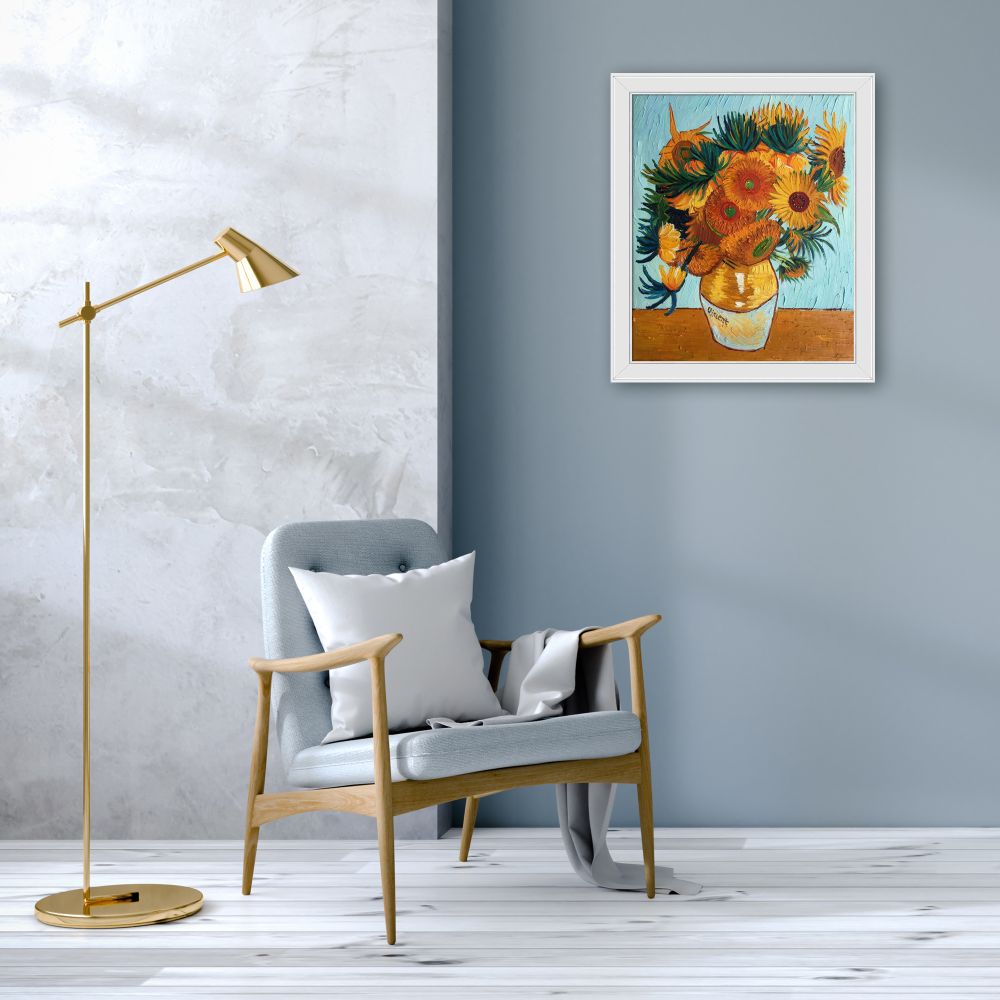 Framed sunflower wall art in a modern minimalist living room with a grey armchair and gold floor lamp.