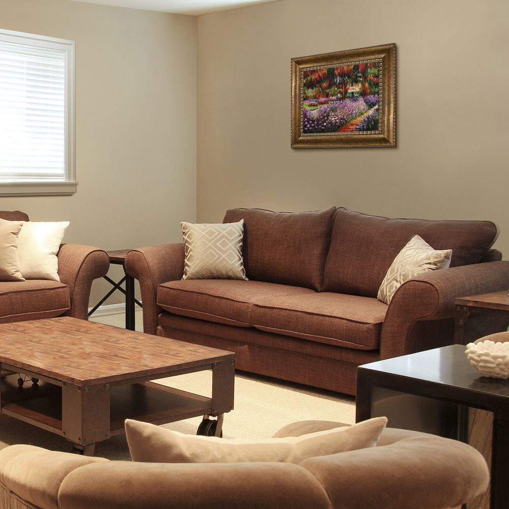 Framed Impressionist garden landscape wall art hanging on a beige wall above a warm brown sofa in a cozy, modern living room setting